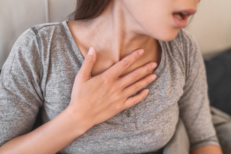 Primo piano di una donna con mano al petto fa fatica a respirare a causa dell'insufficienza respiratoria